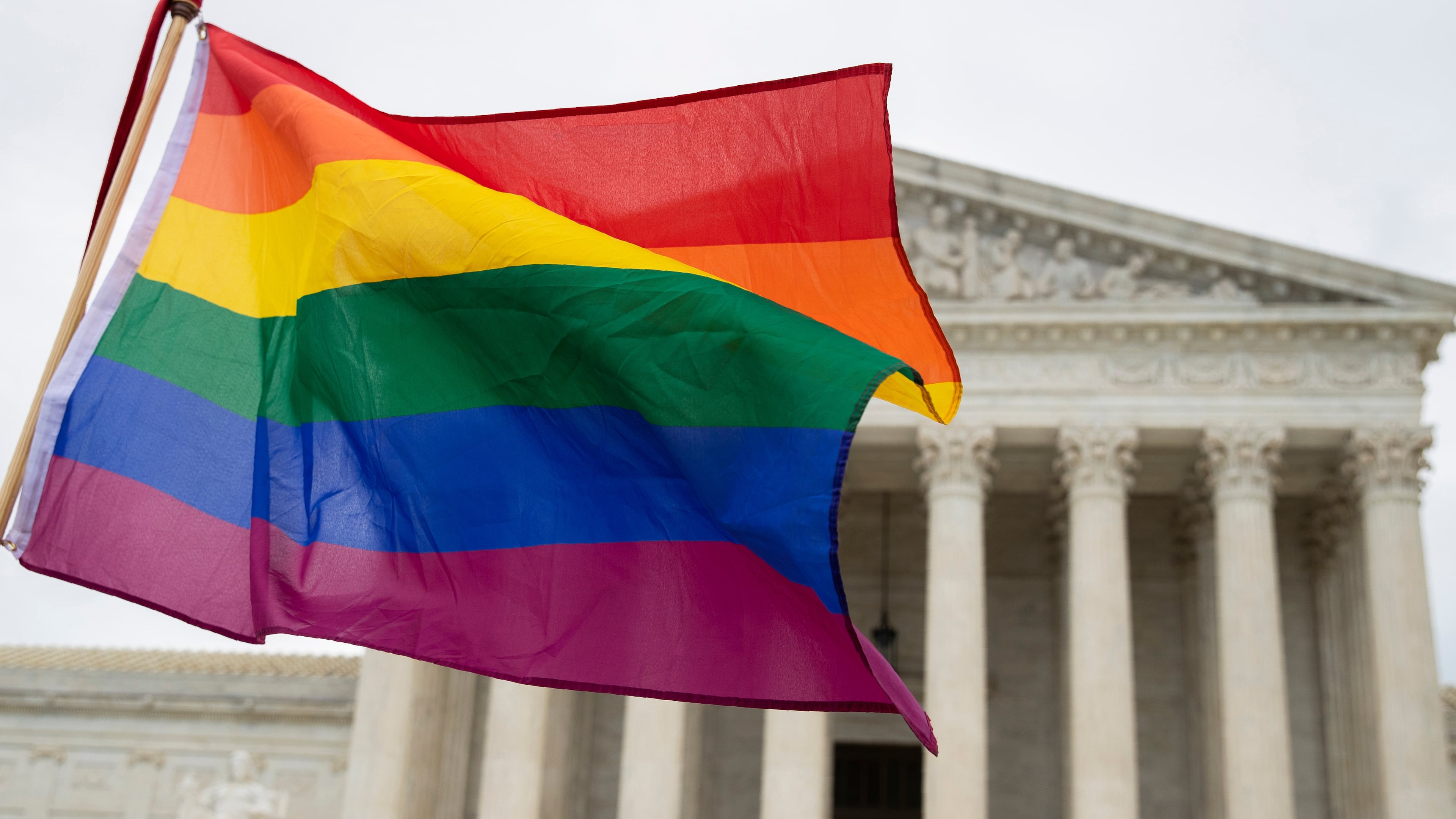 FILE - Supporters of the LGBT wave their flag in front of the U.S. Supreme Cour, Oct. 8, 2019, in Washington. (AP Photo/Manuel Balce Ceneta, File)