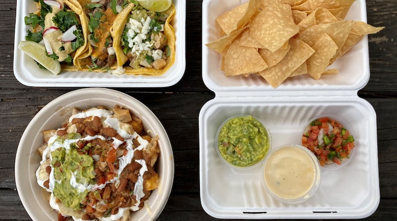 This takeout spread from the Queso Truck includes (clockwise from upper left): chicken, carne asada and pork belly tacos; queso, salsa, guacamole and house-made chips; loaded tots with pork belly. 
Wendell Brock for The Atlanta Journal-Constitution