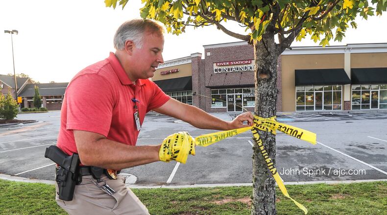 Clayton County police Lt. Thomas Reimers takes down crime-scene tape at the scene of a deadly shooting.