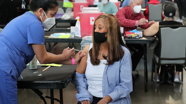 M.D. Anita Shetty (from left) vaccinates Doris Lucas with a Pfizer vaccine while M.D. Steve Budnick prepares to vaccinate Toni Hawkins while operations get under way for Mercedes-Benz Stadium to become the largest Community Vaccination Center in the southeast serving an average of 42,000 citizens a week on Tuesday, March 23, 2021, in Atlanta.  (Curtis Compton / Curtis.Compton@ajc.com)
