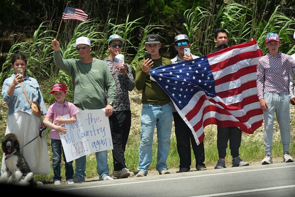 People watch as President Donald Trump and first lady Melania Trump pass in a motorcade in Kerrville, Texas, to monitor flood damage, Friday, July 11, 2025. (AP Photo/Jacquelyn Martin)