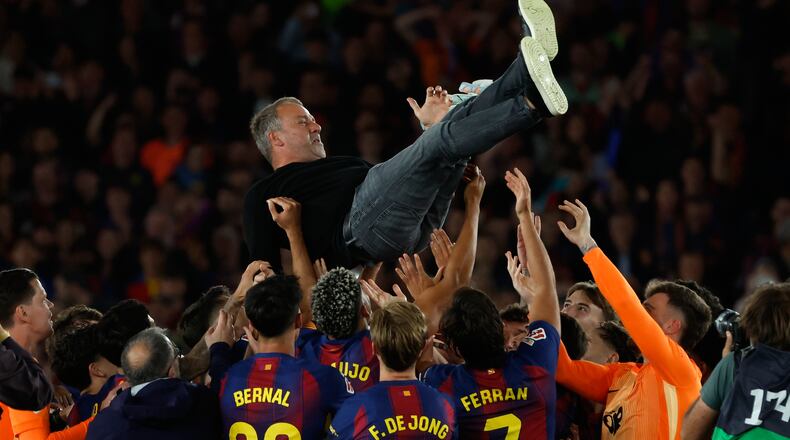 Barcelona head coach Hansi Flick is lifted by his players after winning the Spanish La Liga soccer match against Real Madrid to clinch the Spanish league title in Barcelona, Spain, Sunday, May 10, 2026. (AP Photo/Joan Monfort)