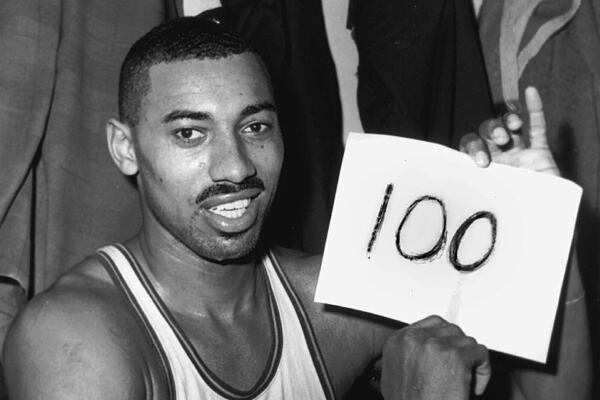 FILE - In this March 2, 1962 file photo, Wilt Chamberlain of the Philadelphia Warriors holds a sign reading "100" in the dressing room in Hershey, Pa., after he scored 100 points, as the Warriors defeated the New York Knickerbockers 169-147. (AP Photo/Paul Vathis, File)