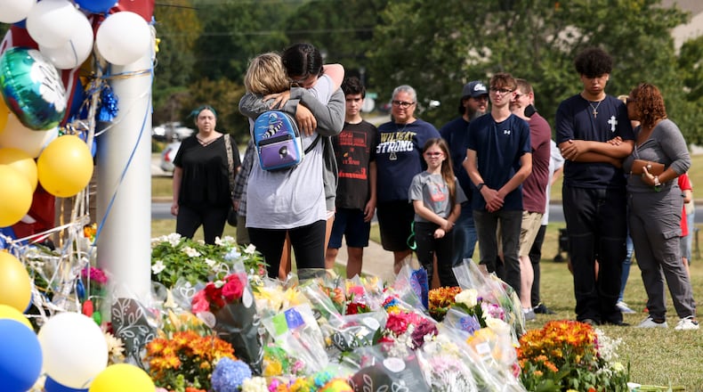 Mourners visit a makeshift memorial at the flagpole at Apalachee High School last week. (Jason Getz/The Atlanta Journal-Constitution)
