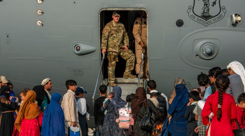 FILE - In this Aug. 22, 2021 file photo provided by the U.S. Air Force, service members stand at a doorway as Afghan evacuees prepare to board an aircraft, Aug. 22, 2021, at Al Udeid Air Base, Qatar. (Airman 1st Class Kylie Barrow/U.S. Air Force via AP, File)