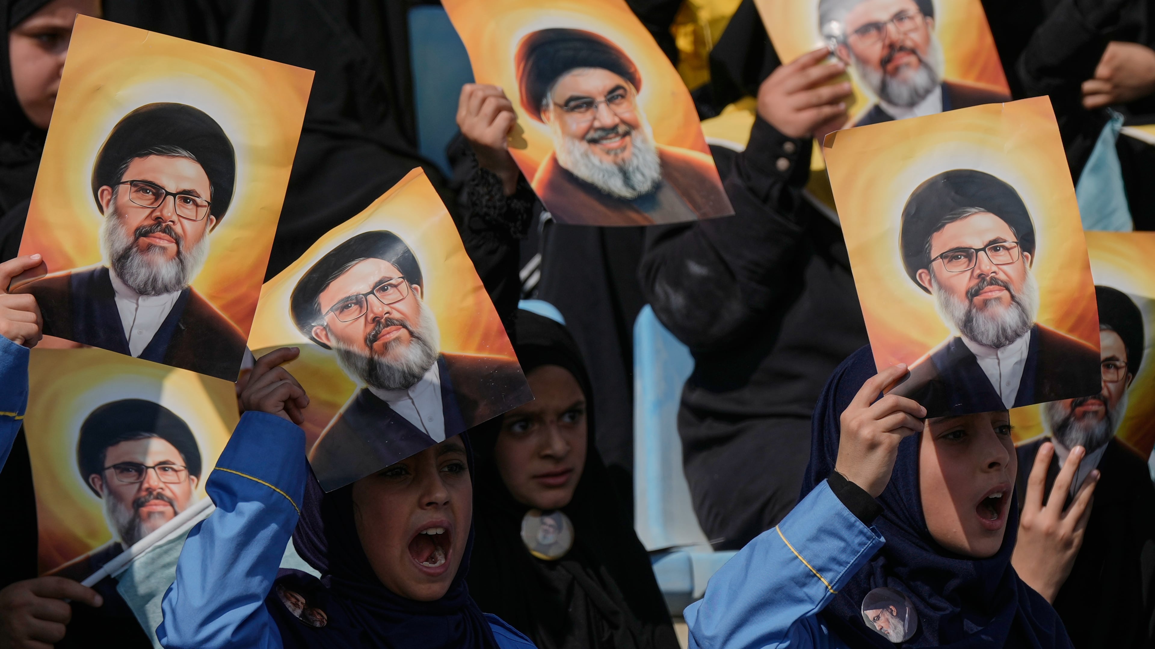 Hezbollah's al-Mahdi Scouts hold pictures of Hezbollah's former leader Hassan Nasrallah and his cousin and successor Hashem Safieddine, to marking the first anniversary of their assassination, who were killed in Israeli airstrikes, at Sports City Stadium in Beirut, Lebanon, Sunday, Oct. 12, 2025. (AP Photo/Bilal Hussein)