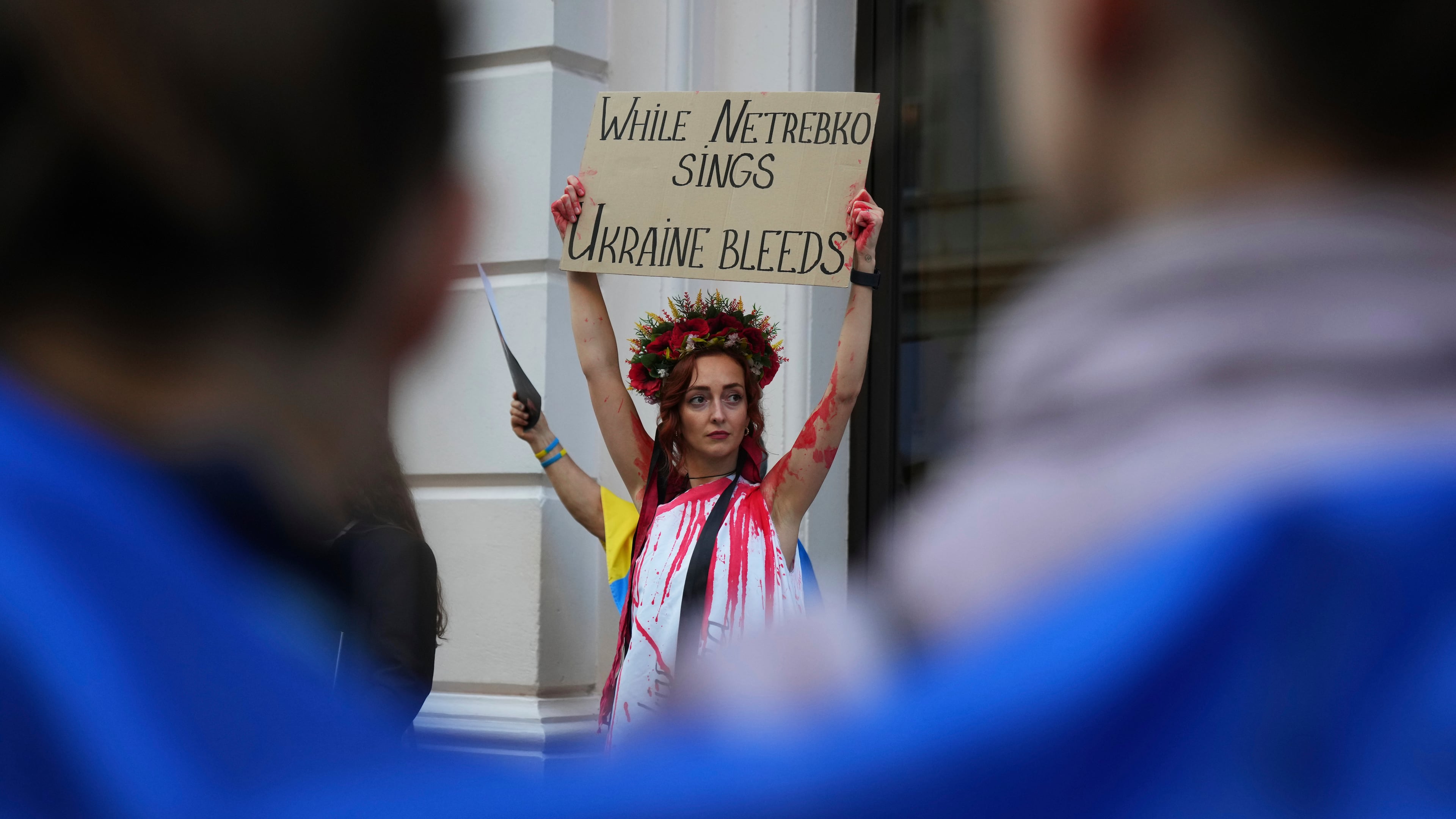 Pro-Ukraine protesters hold up placards and flags during a demonstration against the Royal Opera House in London, as the house had set an Russian opera singer to perform the lead in Puccini's Tosca, Thursday, Sept. 11, 2025. (AP Photo/Joanna Chan)