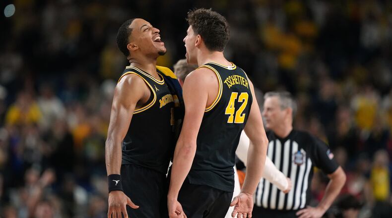 Michigan's Nimari Burnett, left, and Will Tschetter (42) celebrate during the second half of an NCAA college basketball tournament semifinal game against Arizona at the Final Four, Saturday, April 4, 2026, in Indianapolis. (AP Photo/Michael Conroy)