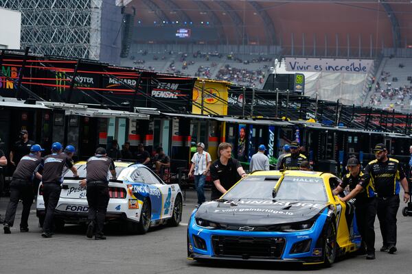 Mechanics of Justin Haley, right, and Noah Gragson push their cars on the paddock prior to a practice session for the NASCAR Cup Series auto race at the Hermanos Rodriguez race track in Mexico City, Friday, June 13, 2025. (AP Photo/Fernando Llano)