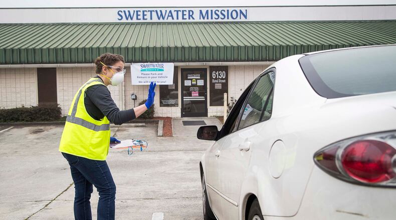 03/19/2020 -- Austell, Georgia -- Sweetwater Mission Clothing Program Coordinator, Mary Beth Alexander receives a patron's information during the food distribution "drive-thru" at Sweetwater Mission in Austell, Thursday, March, 19, 2020. Alexander, along with other volunteers and employees, wore protective wear while facilitating the food distribution. Normally patrons are allowed inside the facility to pick their food but operations have shifted due to coronavirus. (ALYSSA POINTER/ALYSSA.POINTER@AJC.COM)