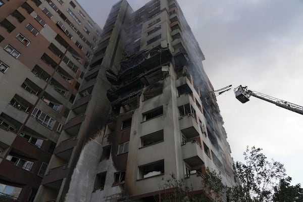 A firefighter stands on a crane at the scene of an explosion at a residence compound after Israeli attacks in Tehran, Friday, June 13, 2025. (AP Photo/Vahid Salemi)
