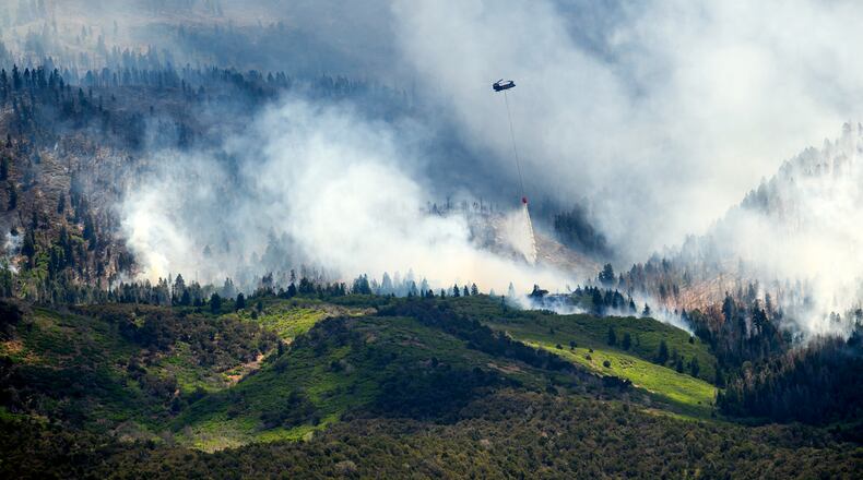 A helicopter drops water on the Cottonwood Fire burning near Beaver, Utah, on Saturday, June 27, 2026. (AP Photo/Noah Berger)