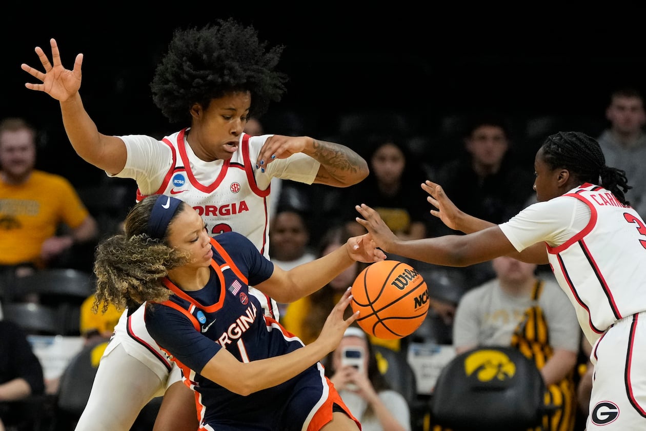 Virginia guard Paris Clark passes between Georgia forward Mia Woolfolk, left, and guard Dani Carnegie, right, during the first half in the first round of the NCAA college basketball tournament, Saturday, March 21, 2026, in Iowa City, Iowa. (Charlie Neibergall/AP)
