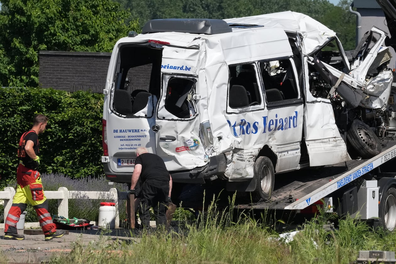 Emergency personnel work at a level crossing to move a van onto a flatbed truck after it collided with a train in Buggenhout, Belgium, Tuesday, May 26, 2026. (AP Photo/Marius Burgelman)