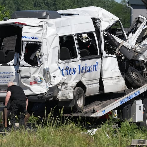 Emergency personnel work at a level crossing to move a van onto a flatbed truck after it collided with a train in Buggenhout, Belgium, Tuesday, May 26, 2026. (AP Photo/Marius Burgelman)