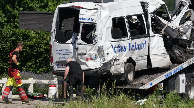 Emergency personnel work at a level crossing to move a van onto a flatbed truck after it collided with a train in Buggenhout, Belgium, Tuesday, May 26, 2026. (AP Photo/Marius Burgelman)