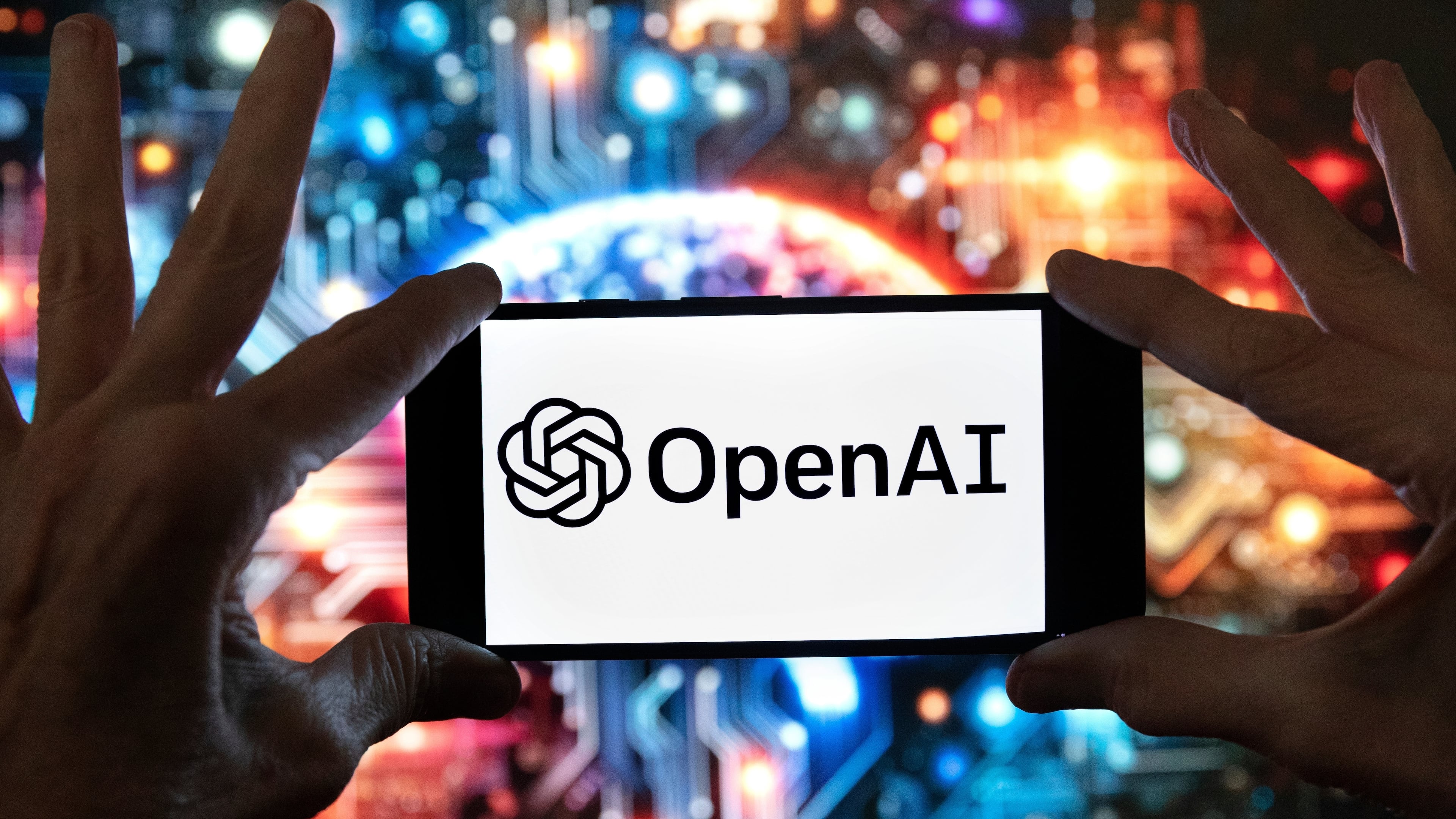 FILE - The OpenAI logo is seen displayed on a cell phone in front of an image on a computer screen generated by ChatGPT's Dall-E text-to-image model, Friday, Dec. 8, 2023, in Boston. (AP Photo/Michael Dwyer, file)