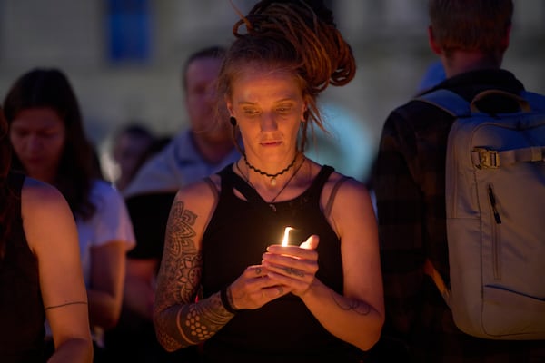 A woman holds a candle for victims of a former student who opened fire at a school, fatally wounding 10 people and injuring many others before taking his own life, in Graz, Austria, Tuesday, June 10, 2025. (AP Photo/Darko Bandic)