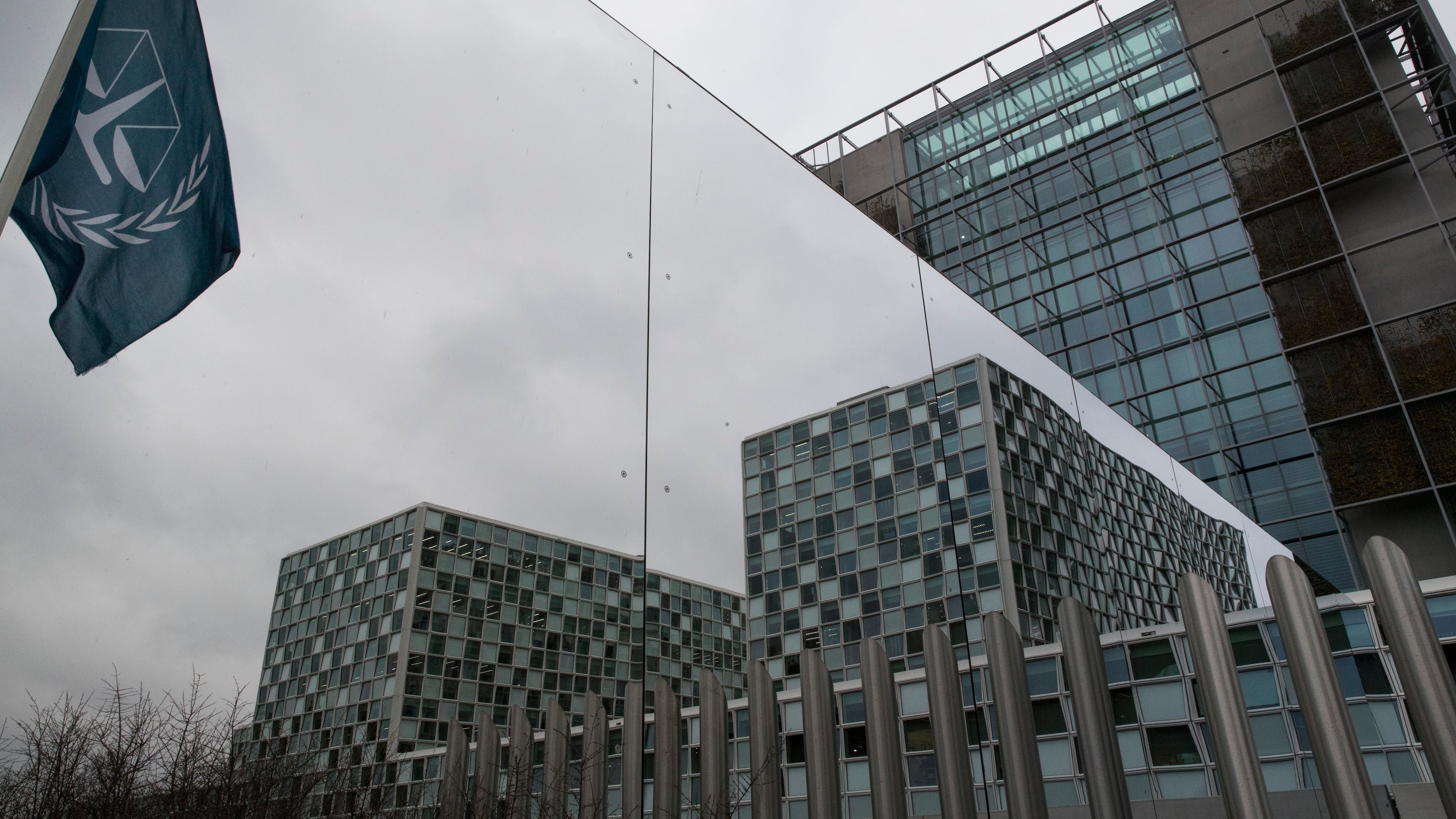 FILE - The flag of the International Criminal Court is reflected in a mirrored wall of the building in The Hague, Netherlands, Jan. 16, 2019. (AP Photo/Peter Dejong, file)