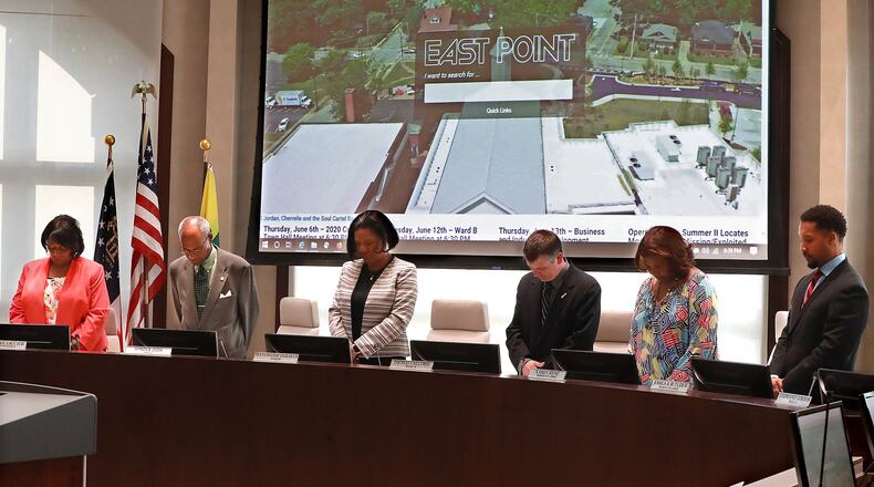 Nanette Saucier (from left), Myron Cook, Mayor Deana Holiday Ingraham, Thomas Calloway, Karen Rene, and Joshua B. Butler IV bow in prayer to open the East Point City Council meeting on Monday, June 3, 2019, in East Point.