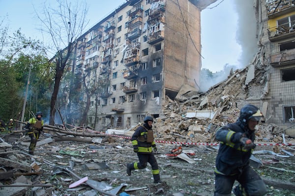 Rescuers run to a shelter to hide from an air raid during Russia's massive missile and drone attack in Kyiv, Ukraine, Tuesday, June 17, 2025. (AP Photo/Efrem Lukatsky)