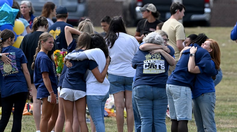 Mourners comfort each other as they visit a makeshift memorial at the flagpole at Apalachee High School on Friday, Sept. 6, 2024, in Winder. (Hyosub Shin/AJC)