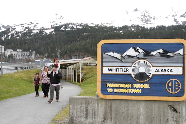 Michael Pese, with daughter Cataleya on his shoulders, and his wife, Tupe Smith, with their son Maximus exit a pedestrian tunnel underneath Whittier, Alaska, May 13, 2025. (AP Photo/Mark Thiessen)