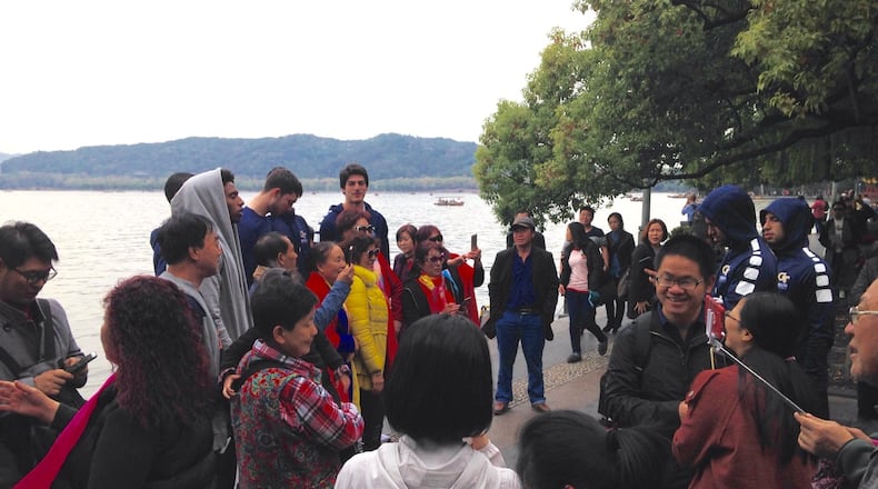 Georgia Tech players pose for pictures on the shores of West Lake Sunday in Hangzhou, China. The team had gone for a walk around the lake on its first fully day in the country, a trip that turned into a photo session. (AJC photo by Ken Sugiura)