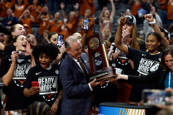 Texas head coach Vic Schaefer and players celebrate with the trophy after they defeated TCU in the Elite Eight of the NCAA college basketball tournament, Monday, March 31, 2025, in Birmingham, Ala. (AP Photo/Butch Dill)