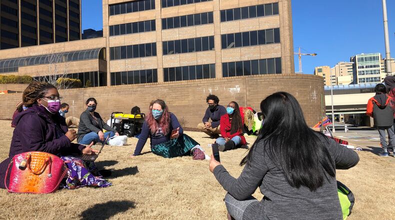 Janna McCrary (left), a science teacher at Peachtree Ridge High School in Gwinnett County, gives a lesson on viruses outside the Georgia Department of Education in downtown Atlanta. (Photo: Alia Milak/AJC)