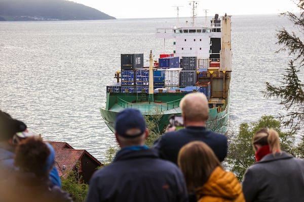 People observe a 135-meter-long container ship that ran aground in the Trondheimsfjord, outside Byneset, in Trondheim, Norway, Thursday May 22, 2025. The container ended up on land near a house on Thursday night. (Jan Langhaug/NTB Scanpix via AP)