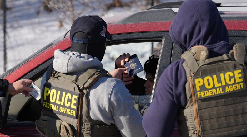 Federal agents make a traffic stop on a U.S. citizen as they provide their identification including a passport and drivers license, Tuesday, Jan. 27, 2026, in Minneapolis. (AP Photo/Adam Gray)