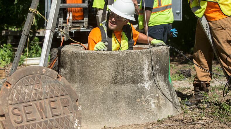 After demonstrating the county's sewer cleaning efforts by sending a member down the manhole, they pull up the crew member from the sewer on June 28, 2017 in Dunwoody, GA. Chad Rhym/ Chad.Rhym@AJC.com
