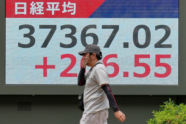 A person walks in front of an electronic stock board showing Japan's Nikkei index at a securities firm Monday, May 26, 2025, in Tokyo. (AP Photo/Eugene Hoshiko)