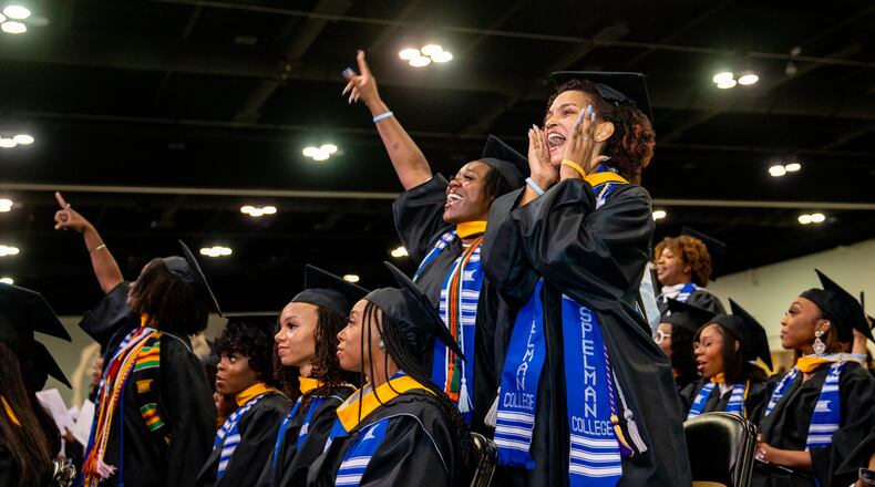 Graduates Raven Rouseau (hand up) and Katharine Ross (right) sing along with “A Choice to Change the World” during Spelman College’s commencement at the Georgia International Convention Center on Sunday, May 21, 2023.  (Jenni Girtman for The Atlanta Journal-Constitution)