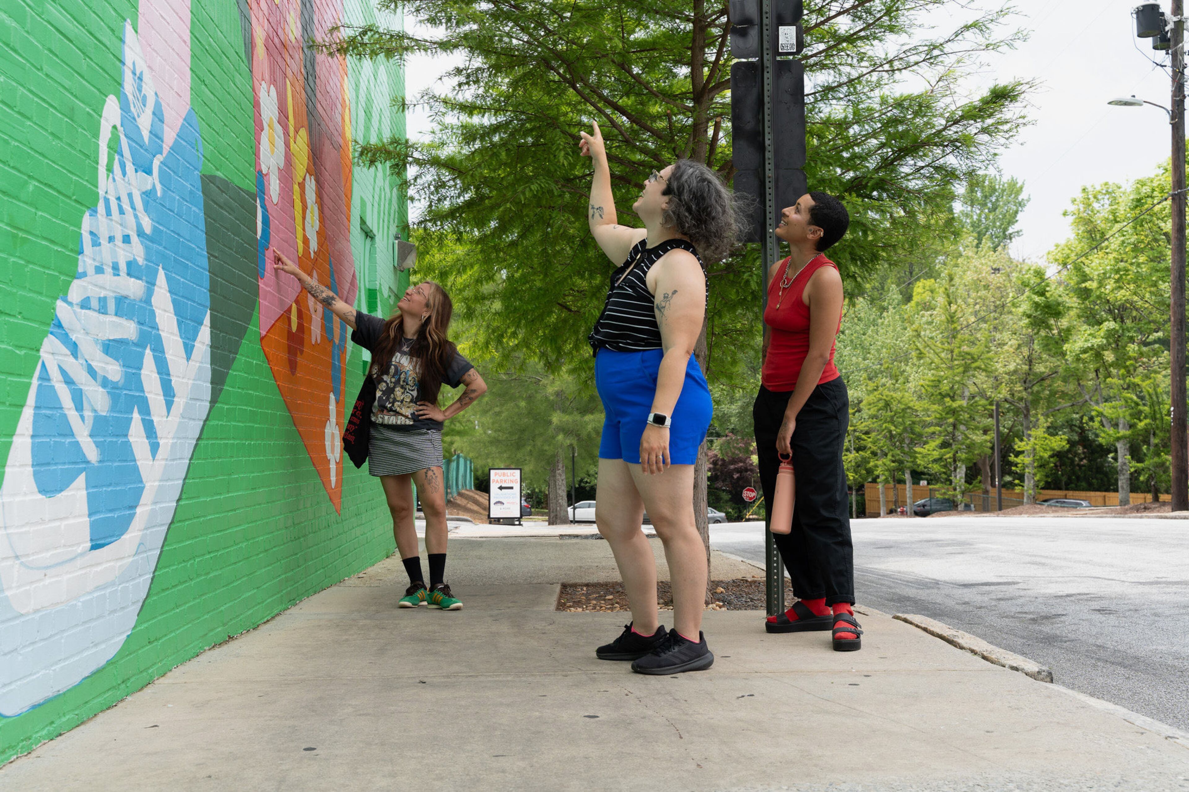 Onlookers admire a Living Walls mural by Atlanta artist Yuzly Mathurin. The mural on the corner of Cherokee Avenue and Memorial Drive shows a determined African American woman in a flowered kimono and the words “Spread Love Not Hate.” (Pilar Linares Photography)