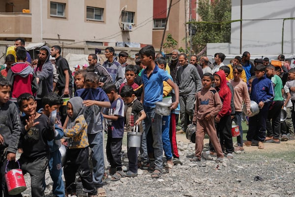 Palestinians wait for donated food at a distribution center in Nuseirat, central Gaza Strip, Friday, April 11, 2025. (AP Photo/Abdel Kareem Hana)