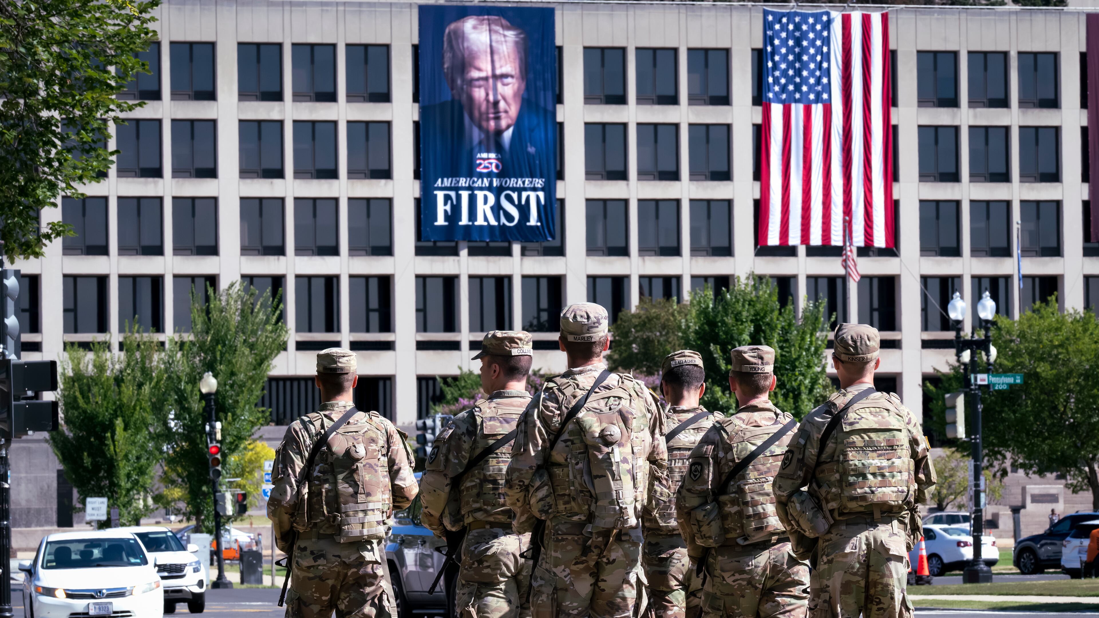 Armed National Guard soldiers from West Virginia patrol the Mall near the Labor Department in Washington, where a poster of President Donald Trump is displayed, Tuesday, Aug. 26, 2025. (J. Scott Applewhite/AP)