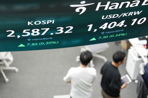 Dealers walk past near the screens showing the Korea Composite Stock Price Index (KOSPI), left, and the foreign exchange rate between U.S. dollar and South Korean won at a dealing room of Hana Bank in Seoul, South Korea, Friday, May 9, 2025. (AP Photo/Lee Jin-man)