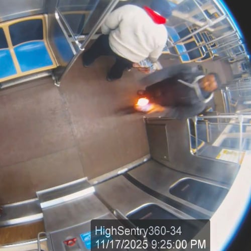 This still image taken from Chicago Transit Authority surveillance footage and included in a federal court record shows a man who federal authorities identified as Lawrence Reed holding a flaming bottle and approaching a passenger, far left, on Monday, Nov. 17, 2025, on a Chicago Blue Line train. (Chicago Transit Authority/U.S. District Court Northern District of Illinois via AP)