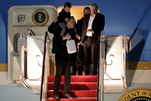 Elon Musk, left, carries his son, X Æ A-Xii, down the stairs of Air Force One upon President Donald Trump's arrival at Joint Base Andrews, Md., Sunday, April 13, 2025. (AP Photo/Luis M. Alvarez)