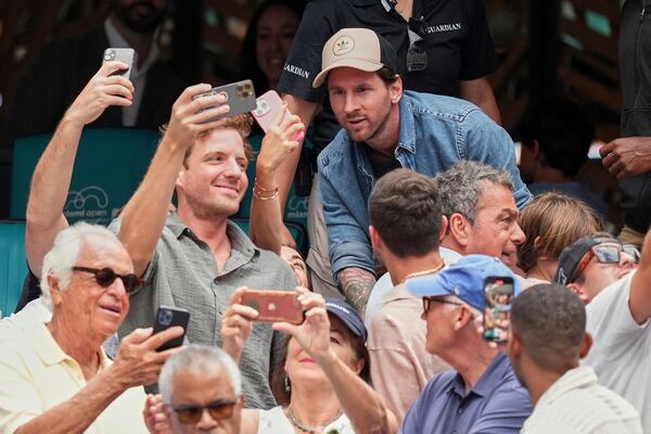 Soccer star Lionel Messi, top, poses for selfies with fans at the end of a semifinal match between Novak Djokovic, of Serbia, and Grigor Dimitrov, of Bulgaria, at the Miami Open tennis tournament, Friday, March 28, 2025, in Miami Gardens, Fla. (AP Photo/Rebecca Blackwell)