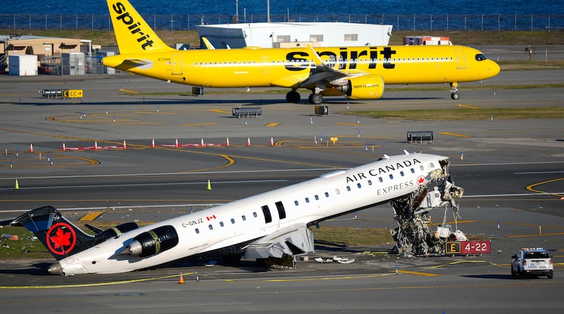 A Spirit Airlines jet taxis past an Air Canada Express jet sitting on the side of a runway, Tuesday, March 24, 2026, where it had collided with a Port Authority fire truck Sunday night at LaGuardia Airport in New York. (AP Photo/Yuki Iwamura)