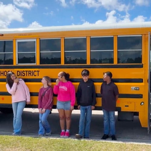 Five middle school students, who helped stop a bus after their driver passed out during a medical emergency, stand outside a bus in Hancock County, Miss., on Thursday, April 23, 2026. (WLOX via AP)
