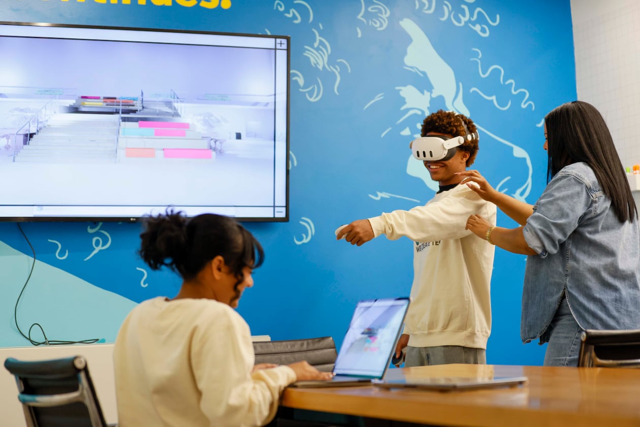 Shana Sanders, founder and CEO of We Create Tech, works with King Arrington as Natasha Narine navigates a 3D space during a VR program class at Polywood. Sanders and her team have led immersive experiences in coding and AI, and are now pioneering a culturally responsive VR education space. (Miguel Martinez/AJC 2025)