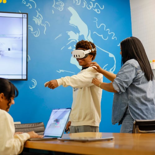 Shana Sanders, founder and CEO of We Create Tech, works with King Arrington as Natasha Narine navigates a 3D space during a VR program class at Polywood. Sanders and her team have led immersive experiences in coding and AI, and are now pioneering a culturally responsive VR education space. (Miguel Martinez/AJC 2025)