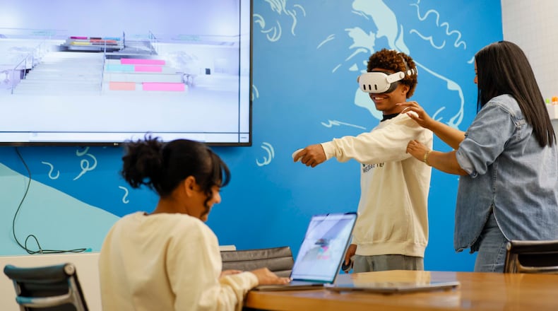 Shana Sanders, founder and CEO of We Create Tech, works with King Arrington as Natasha Narine navigates a 3D space during a VR program class at Polywood. Sanders and her team have led immersive experiences in coding and AI, and are now pioneering a culturally responsive VR education space. (Miguel Martinez/AJC 2025)
