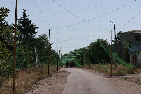 In this photo provided by Ukraine's 65th Mechanized Brigade press service, a local resident walks along the street under an anti-drone net in Orikhiv, Zaporizhzhia region, Ukraine, Tuesday, July 15, 2025. (Andriy Andriyenko/Ukraine's 65th Mechanized Brigade via AP)