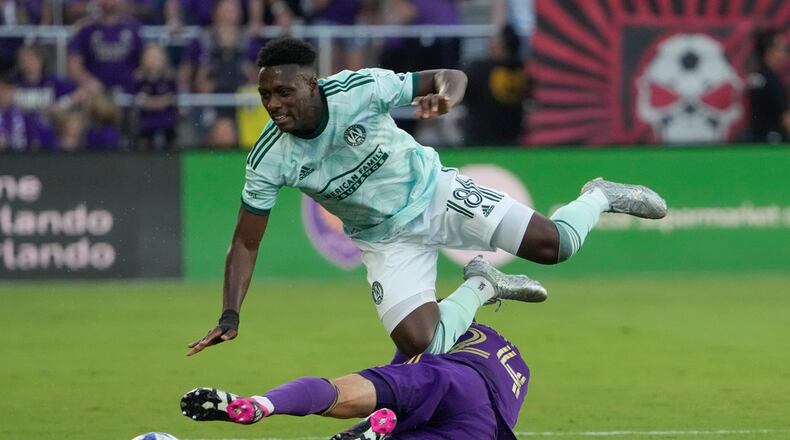 Atlanta United midfielder Derrick Etienne (18) goes over Orlando City defender Kyle Smith, bottom, as they battle for possession of the ball during the first half of an MLS soccer match, Saturday, May 27, 2023, in Orlando, Fla. (AP Photo/John Raoux)