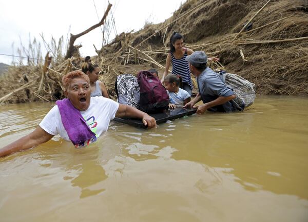 Marta Sostre Vazquez reacts as she starts to wade into the San Lorenzo Morovis river with her family, after the bridge was swept away in Morovis. The family was returning to their home after visiting family on the other side. (Associated Press / Gerald Herbert)